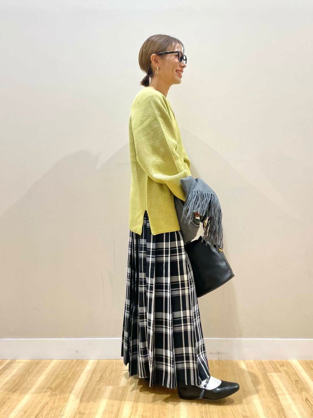 ブラック系のパンプス、ブラック系のショルダーバッグ、イエロー系のニット/セーターを着用したレディースの冬コーディネートの4枚目の写真