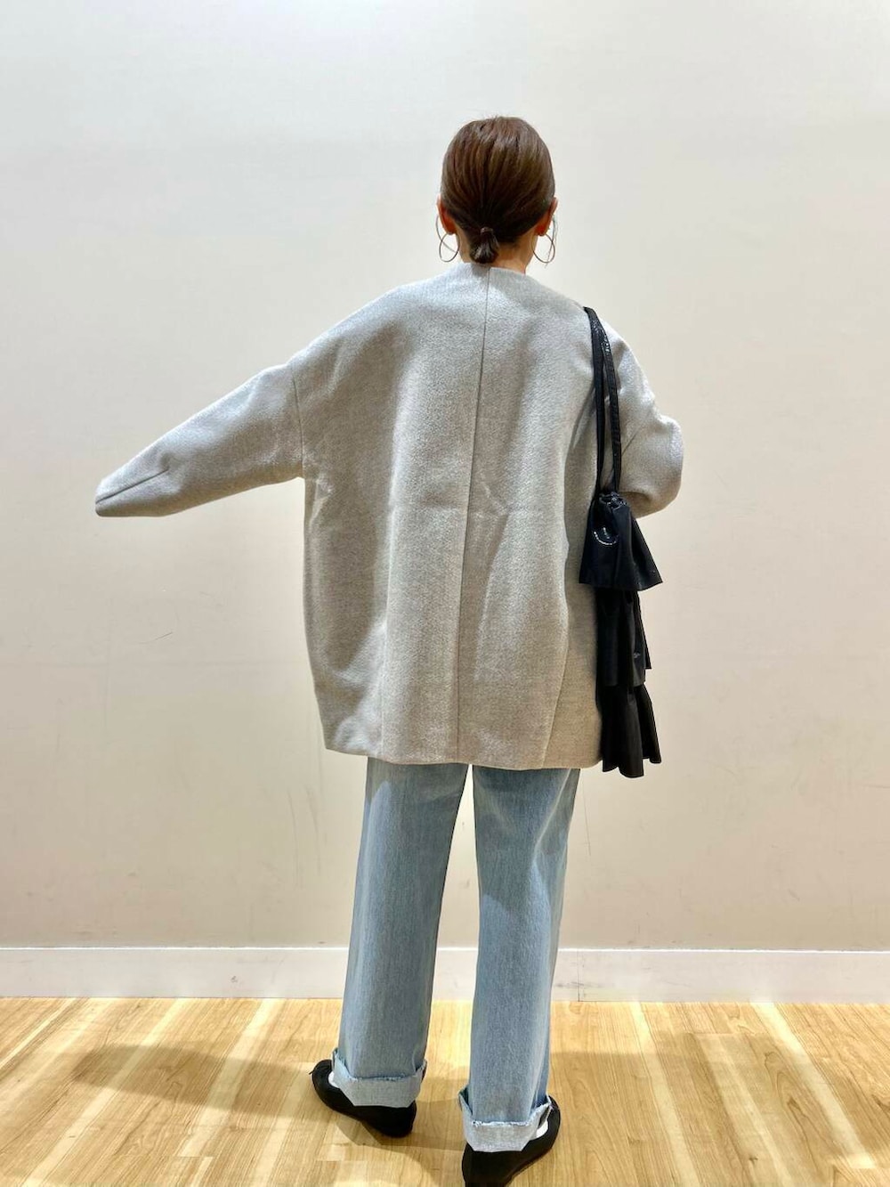 ブラック系のトートバッグ、ブルー系のデニムパンツ、グレー系のノーカラージャケットを着用したレディースの冬コーディネートの3枚目の写真