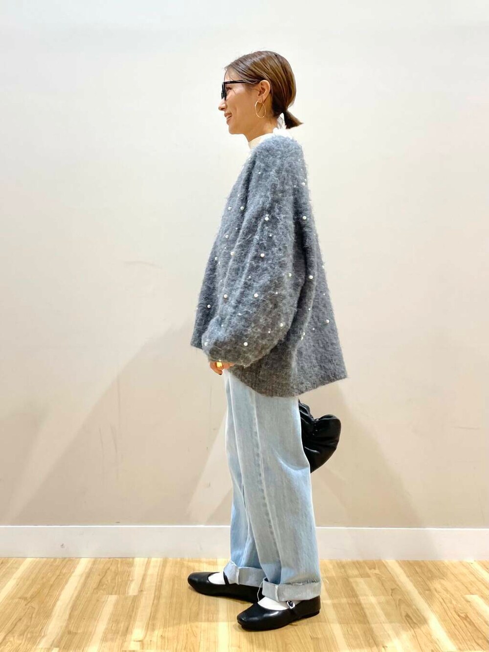 ブラック系のパンプス、ブラック系のハンドバッグ、ブルー系のデニムパンツを着用したレディースの秋コーディネートの6枚目の写真