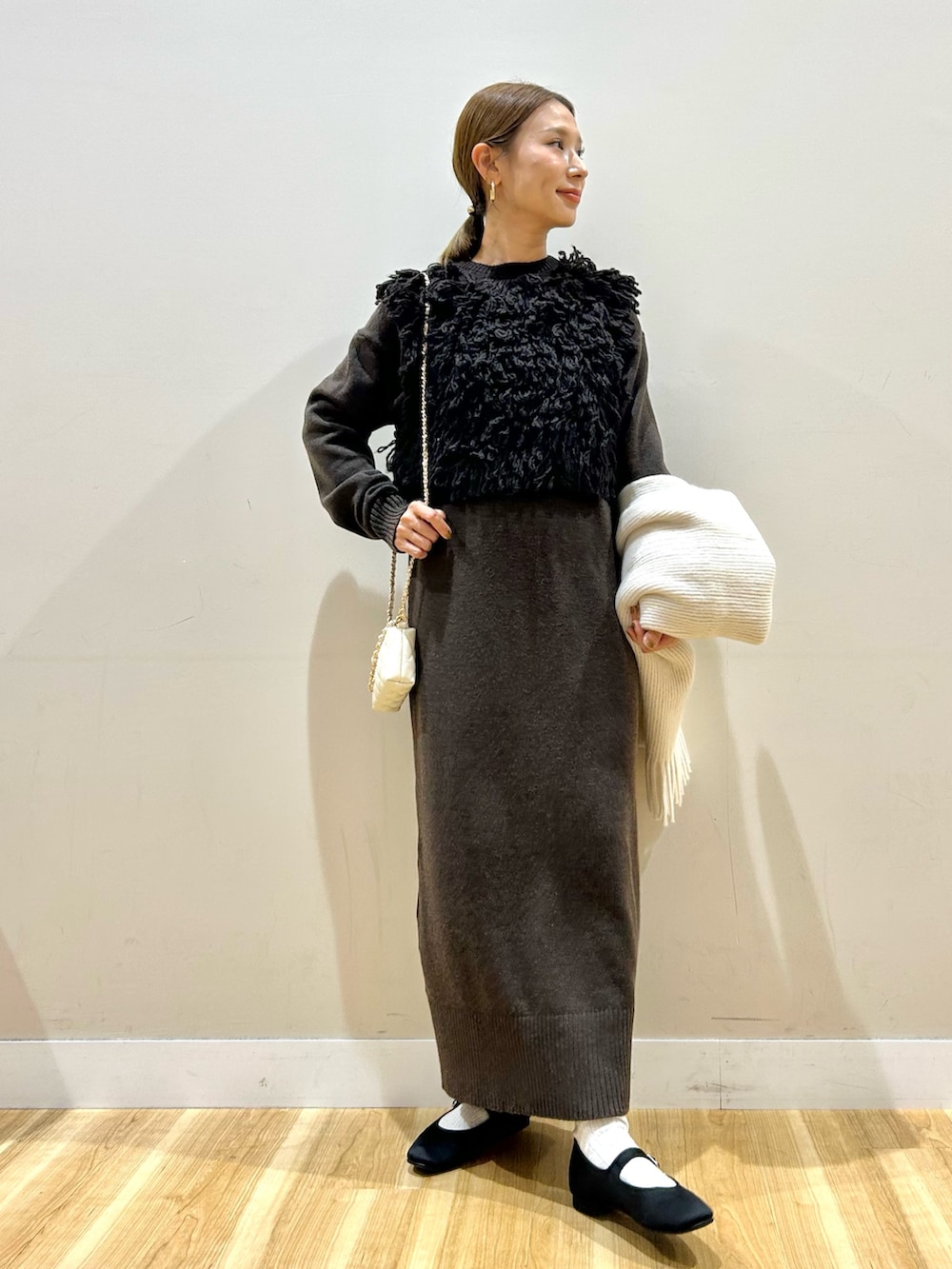 ブラウン系のワンピース、ホワイト系のショルダーバッグ、ブラック系のパンプスを着用したレディースの秋コーディネートの4枚目の写真