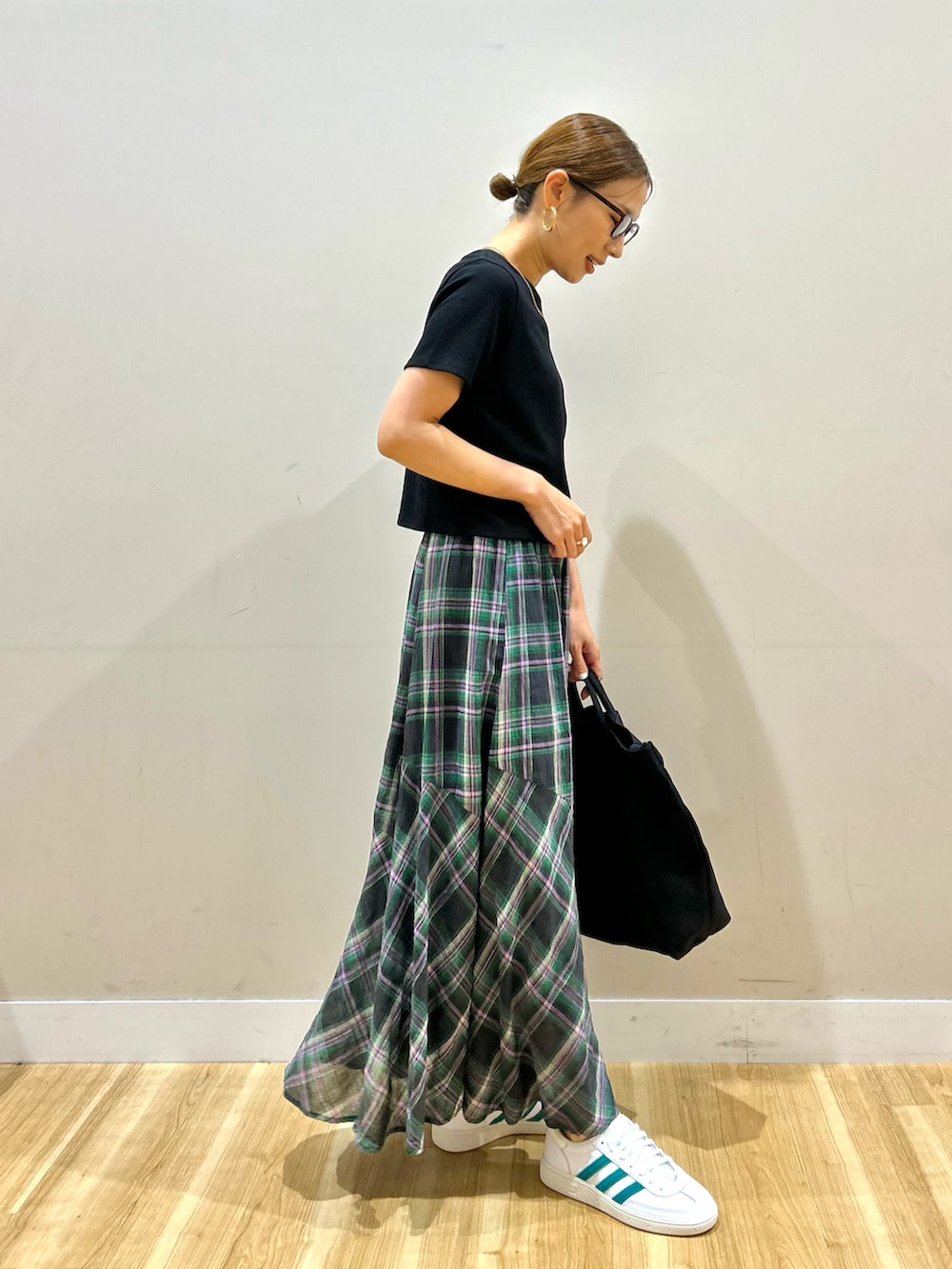ブラック系のTシャツ/カットソー、グリーン系のスカート、ホワイト系のスニーカーを着用したレディースの夏コーディネートの2枚目の写真