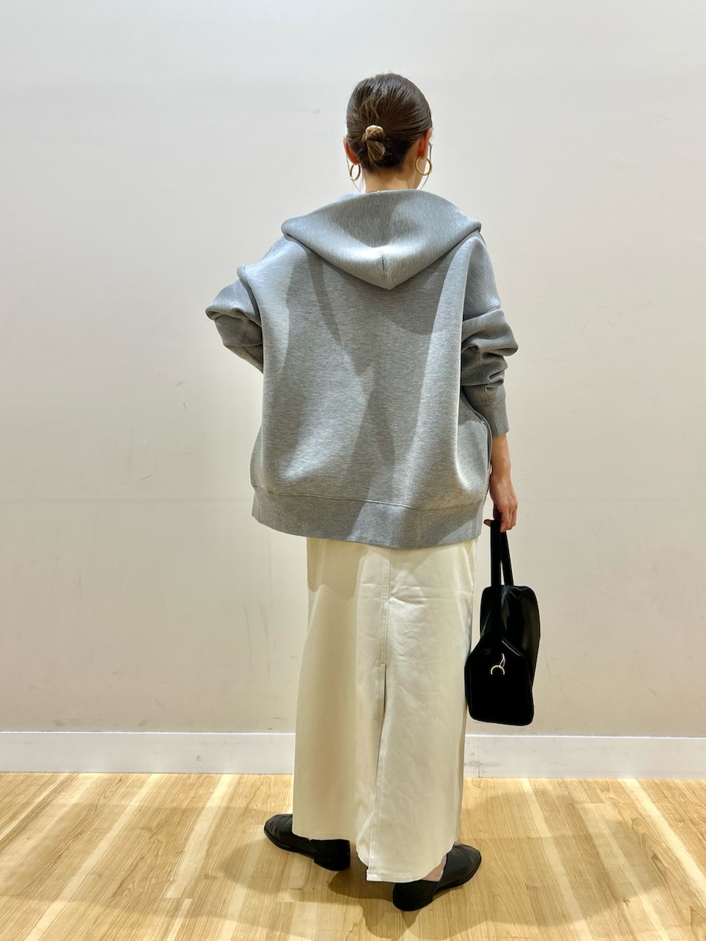 グレー系のパーカー、ブルー系のニット/セーター、ブラック系のスリッポンを着用したレディースの春コーディネートの3枚目の写真