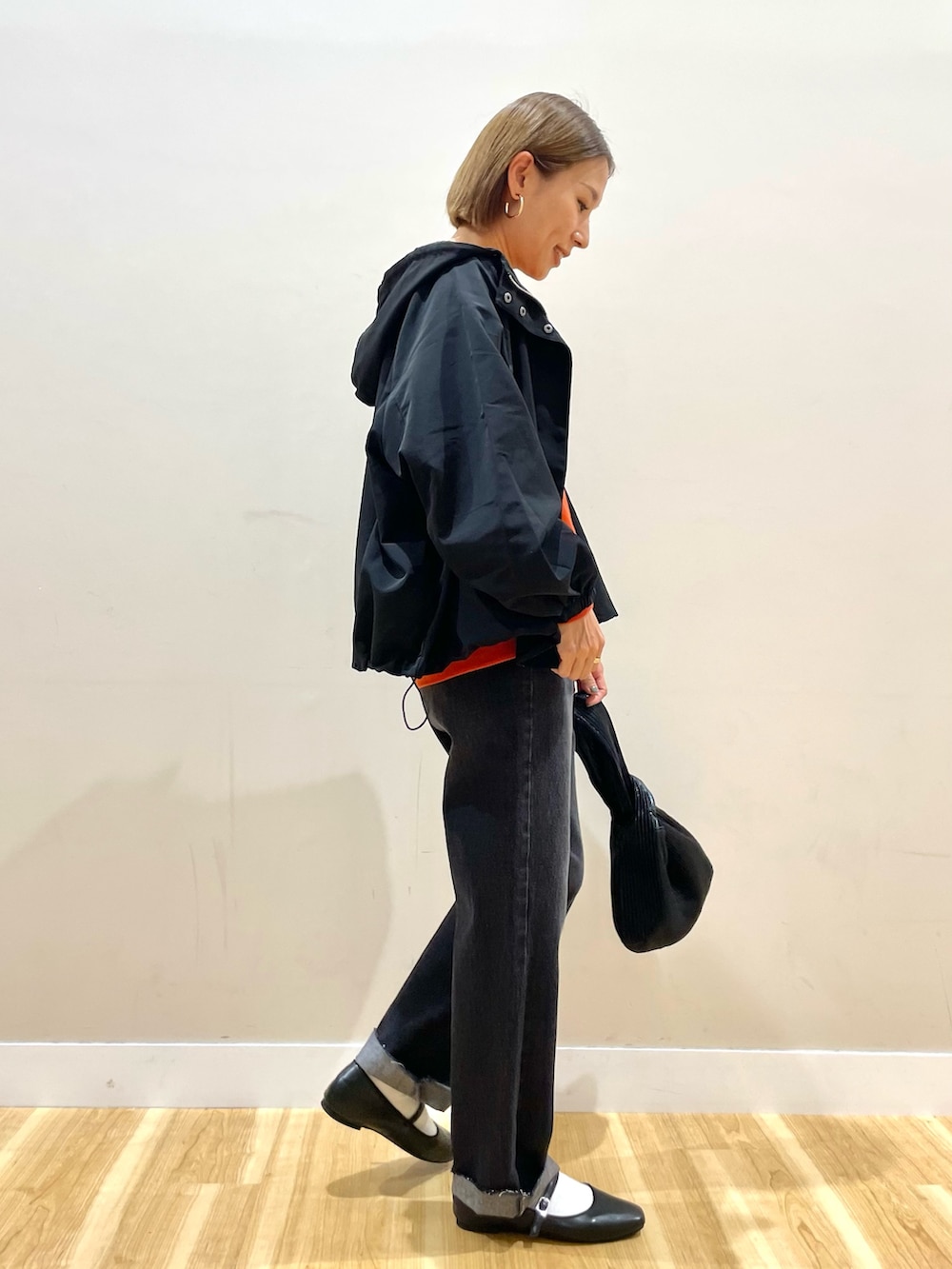 ブラック系のマウンテンパーカー、オレンジ系のスウェット、ブラック系のその他パンツを着用したレディースの秋コーディネートの6枚目の写真