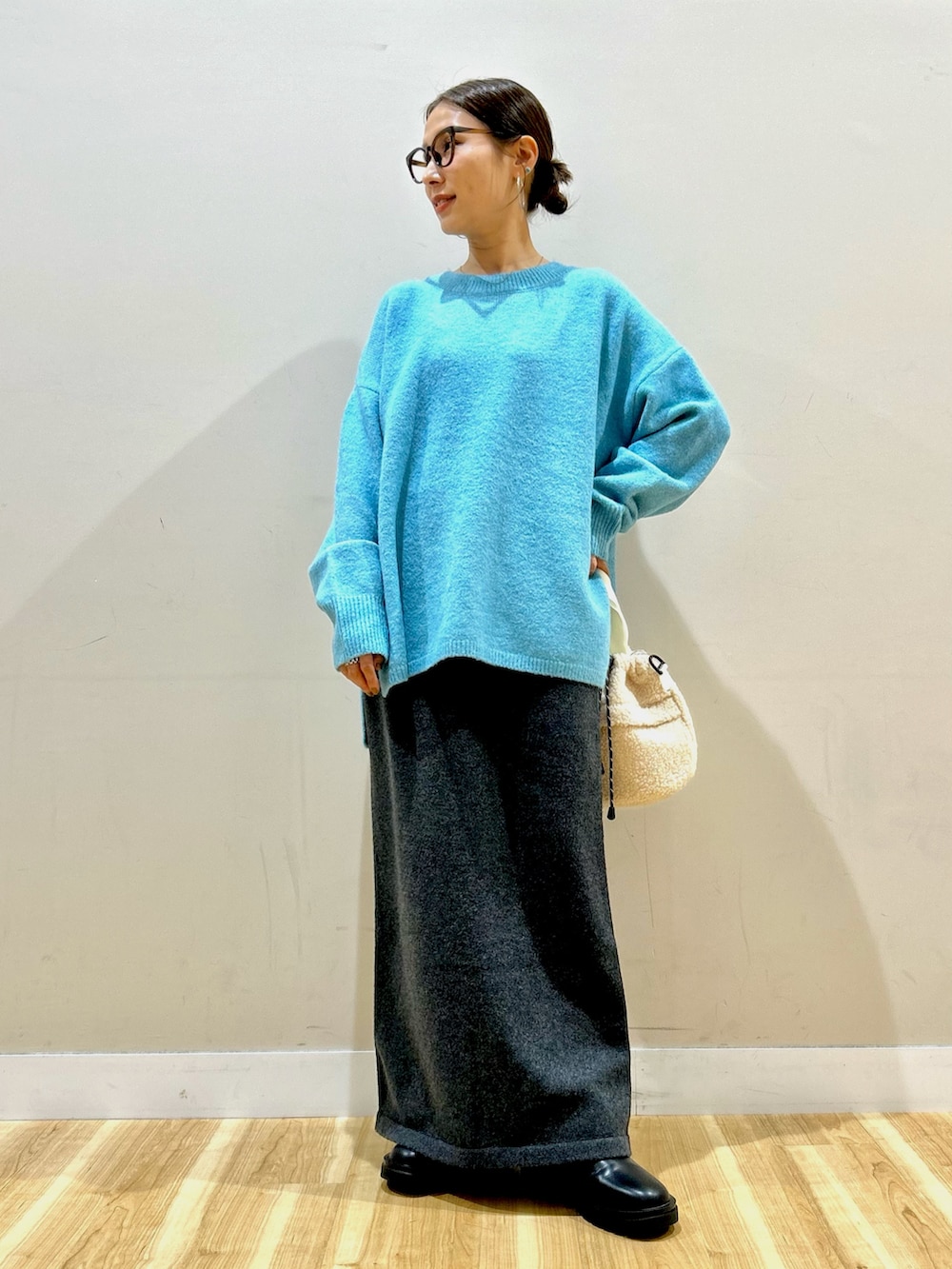 ブラック系のダウンジャケット/コート、ブルー系のニット/セーター、グレー系のスカートを着用したレディースの冬コーディネートの6枚目の写真