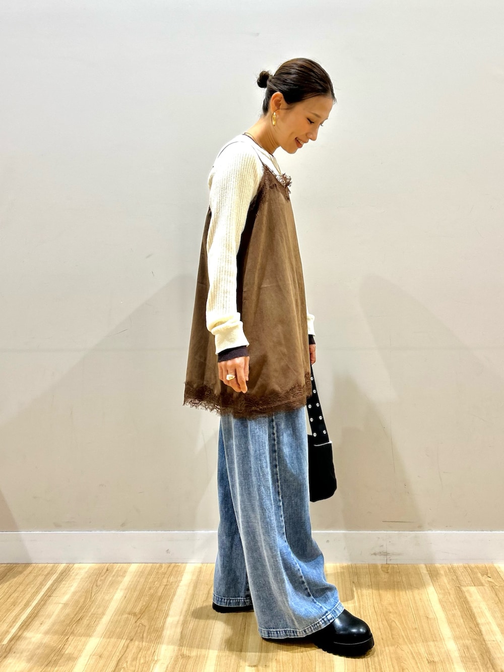 ブルー系のデニムパンツ、ブラック系のショルダーバッグ、ブラック系のブーツを着用したレディースの秋コーディネートの2枚目の写真