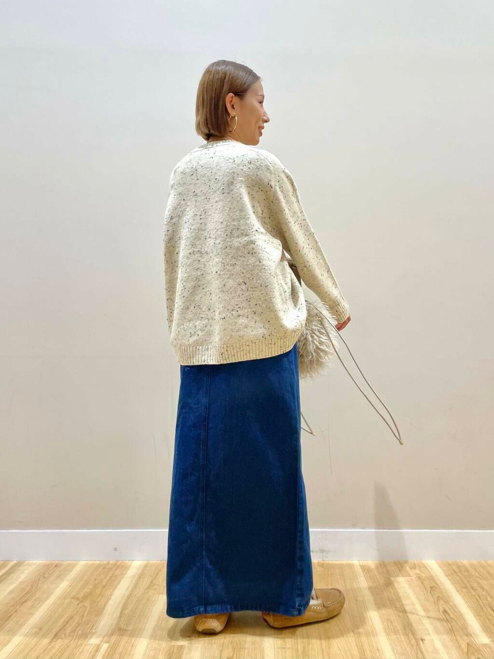 ベージュ系のショルダーバッグ、ブルー系のスカート、ベージュ系のダウンジャケット/コートを着用したレディースの秋コーディネートの9枚目の写真