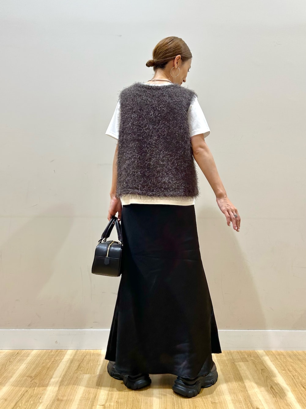 ブラウン系のベスト、ホワイト系のTシャツ/カットソー、ブラック系のスカートを着用したレディースの夏コーディネートの3枚目の写真