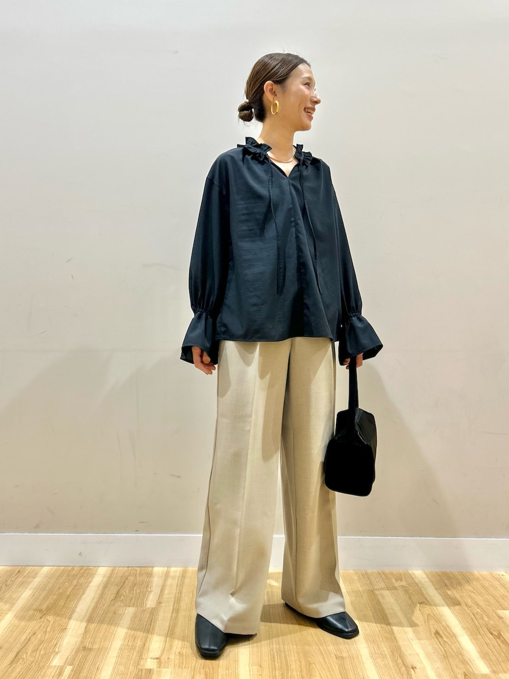 ブラック系のシャツ/ブラウス、ブラック系のトートバッグ、ベージュ系のその他パンツを着用したレディースの春コーディネートの2枚目の写真