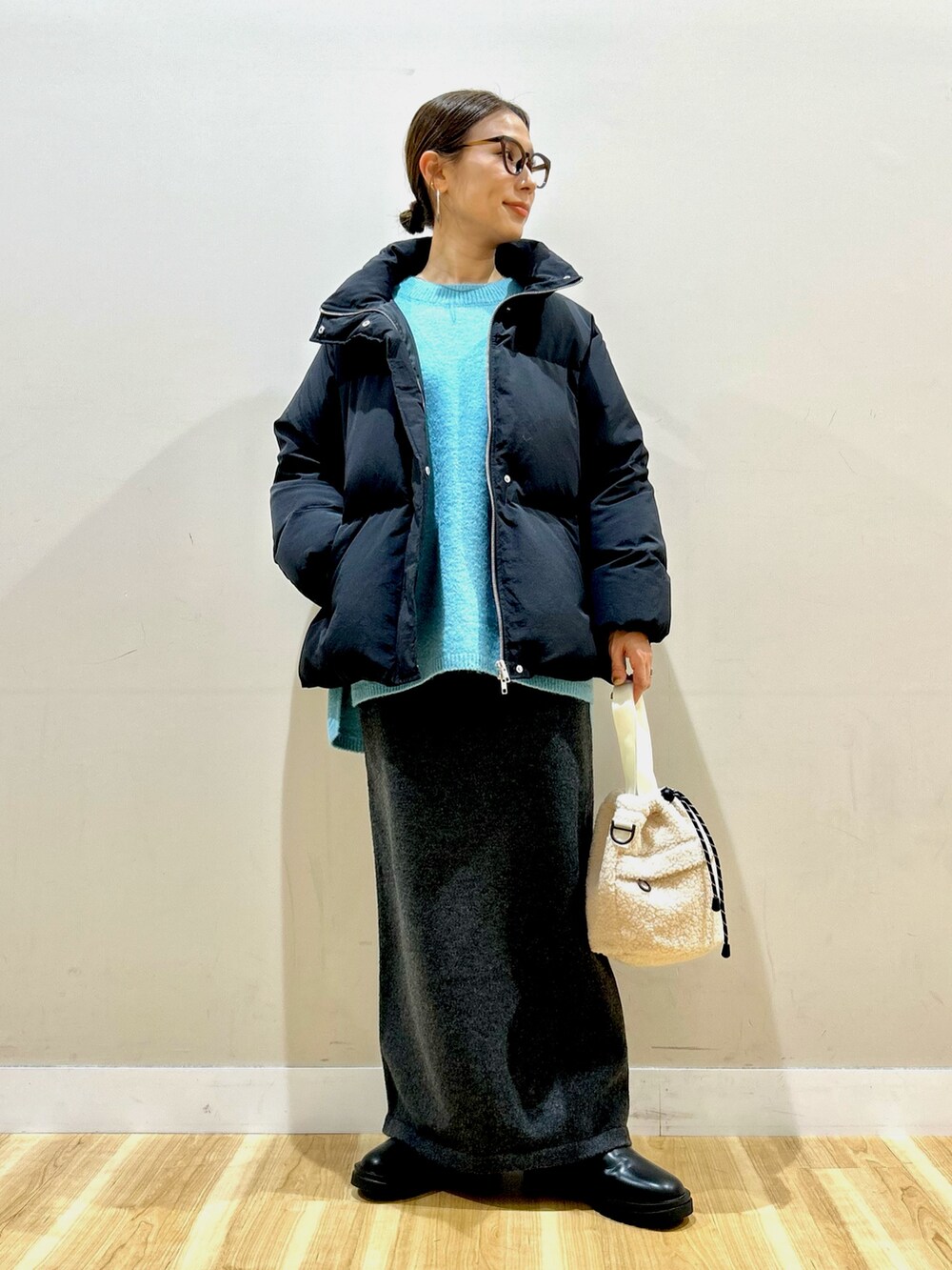 ブラック系のダウンジャケット/コート、ブルー系のニット/セーター、グレー系のスカートを着用したレディースの冬コーディネートの2枚目の写真