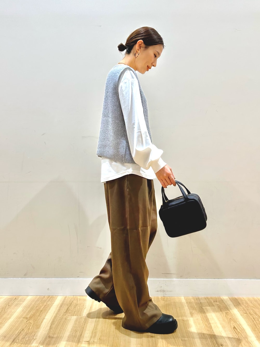 グレー系のベスト、ブラウン系のその他パンツ、ブラック系のボストンバッグを着用したレディースの冬コーディネートの2枚目の写真