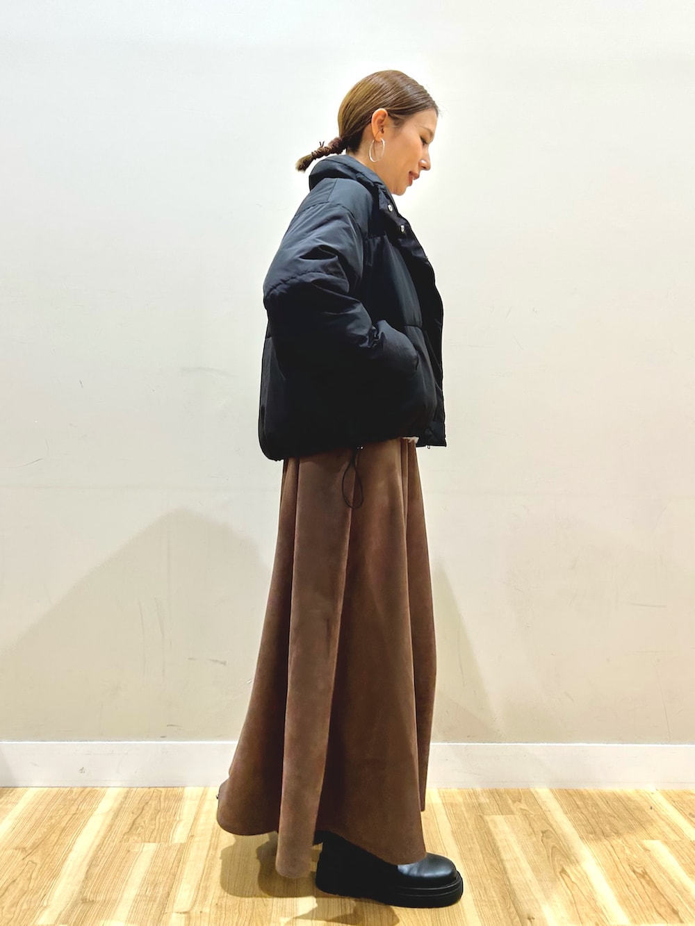 ブラック系のダウンジャケット/コート、グレー系のニット/セーター、ブラウン系のスカートを着用したレディースの秋コーディネートの2枚目の写真