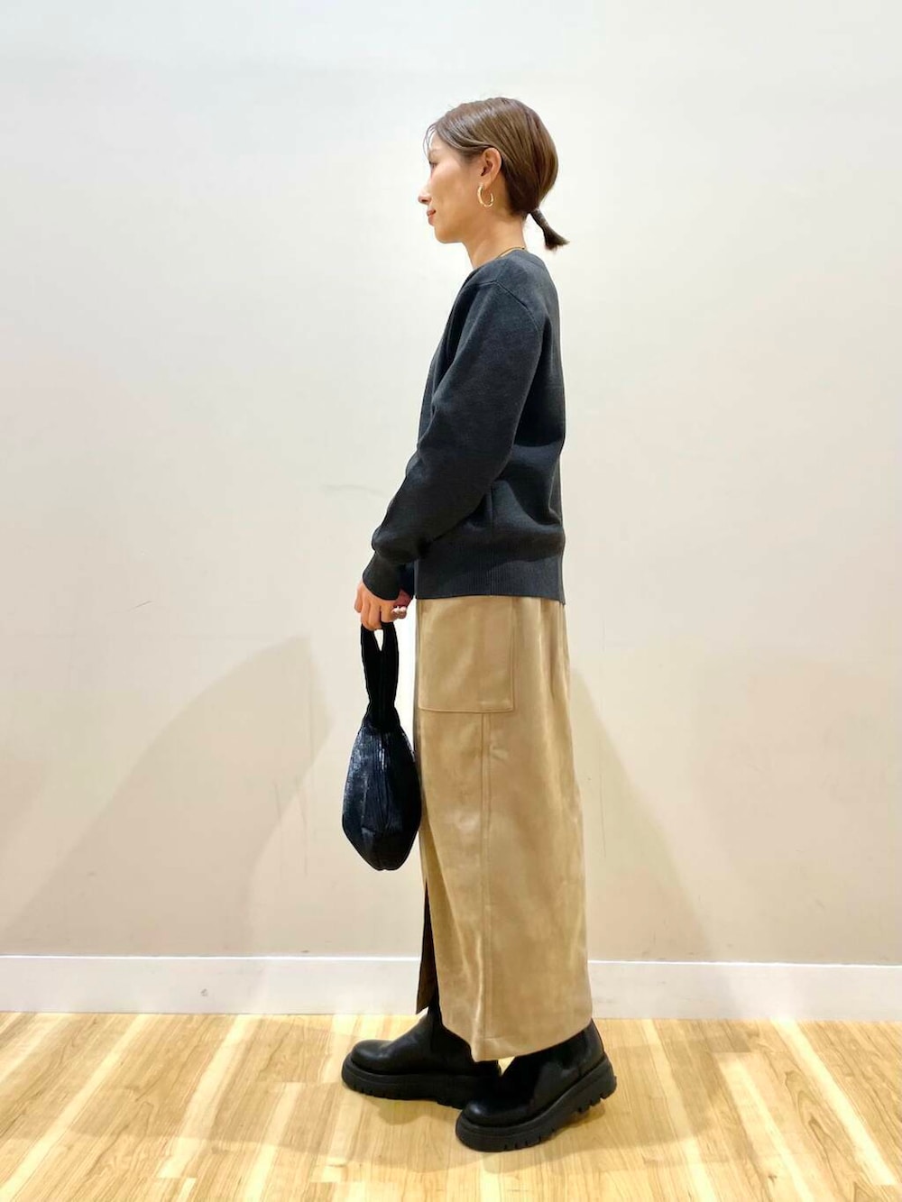 ブラウン系のスカート、ブラック系のハンドバッグ、グレー系のニット/セーターを着用したレディースの冬コーディネートの6枚目の写真