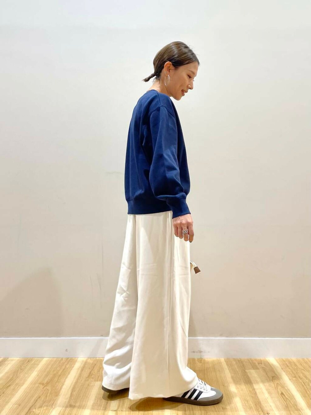 ホワイト系のトートバッグ、ブルー系のスウェット、ホワイト系のスニーカーを着用したレディースの秋コーディネートの3枚目の写真