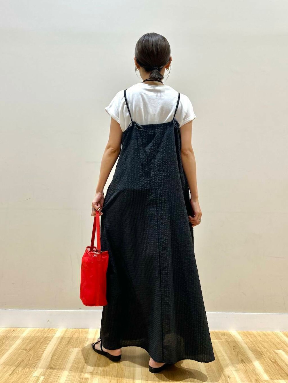 レッド系のショルダーバッグ、ブラック系のサンダル、ブラック系のワンピースを着用したレディースの夏コーディネートの3枚目の写真