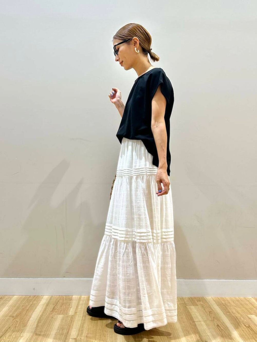 ブラック系のサンダル、ベージュ系のトートバッグ、ホワイト系のスカートを着用したレディースの夏コーディネートの5枚目の写真