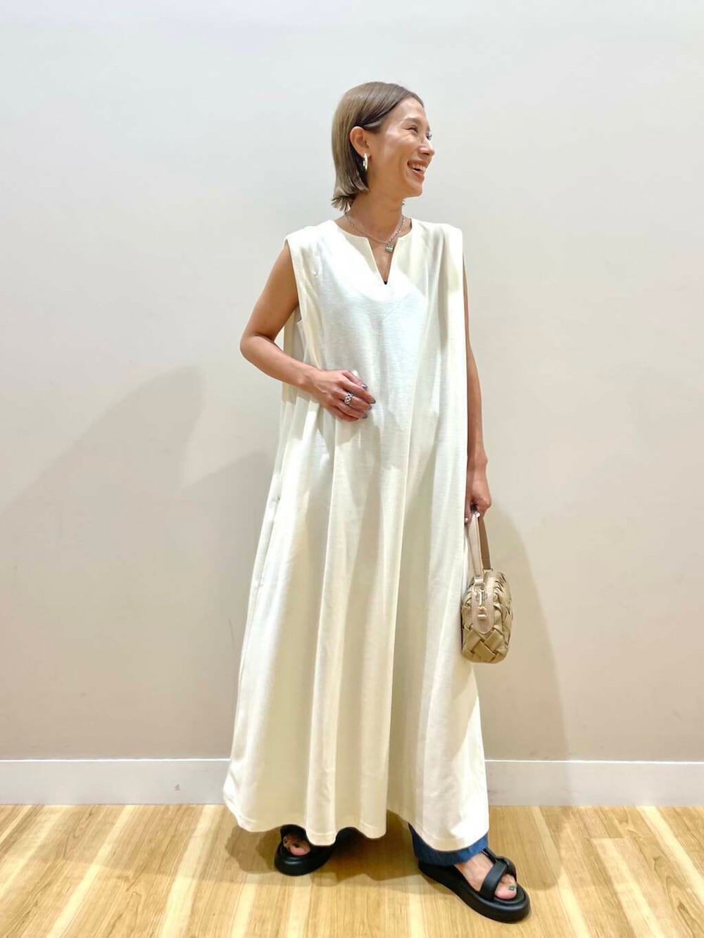 ブラック系のサンダル、ホワイト系のワンピース、ベージュ系のショルダーバッグを着用したレディースの夏コーディネートの2枚目の写真