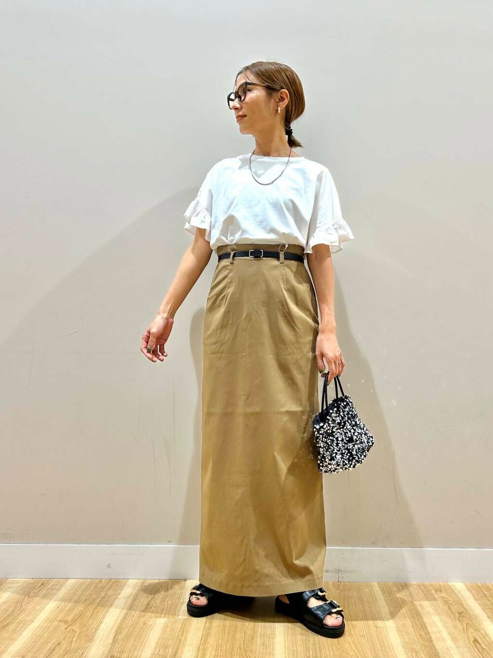 シルバー系のショルダーバッグ、ブラック系のサンダル、ホワイト系のTシャツ/カットソーを着用したレディースの春コーディネートの2枚目の写真