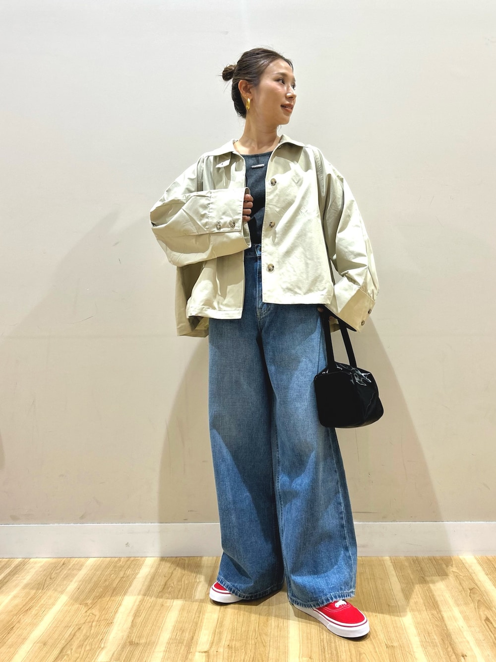 グレー系のステンカラーコート、グレー系のTシャツ/カットソー、ブルー系のデニムパンツを着用したレディースの春コーディネートの4枚目の写真