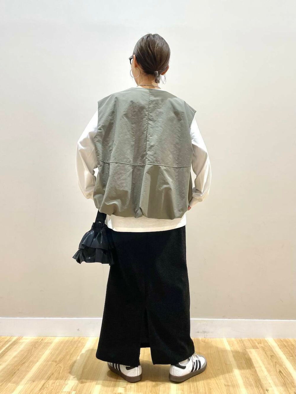 ブラック系のショルダーバッグ、ブラック系のスカート、グリーン系のベストを着用したレディースの秋コーディネートの4枚目の写真