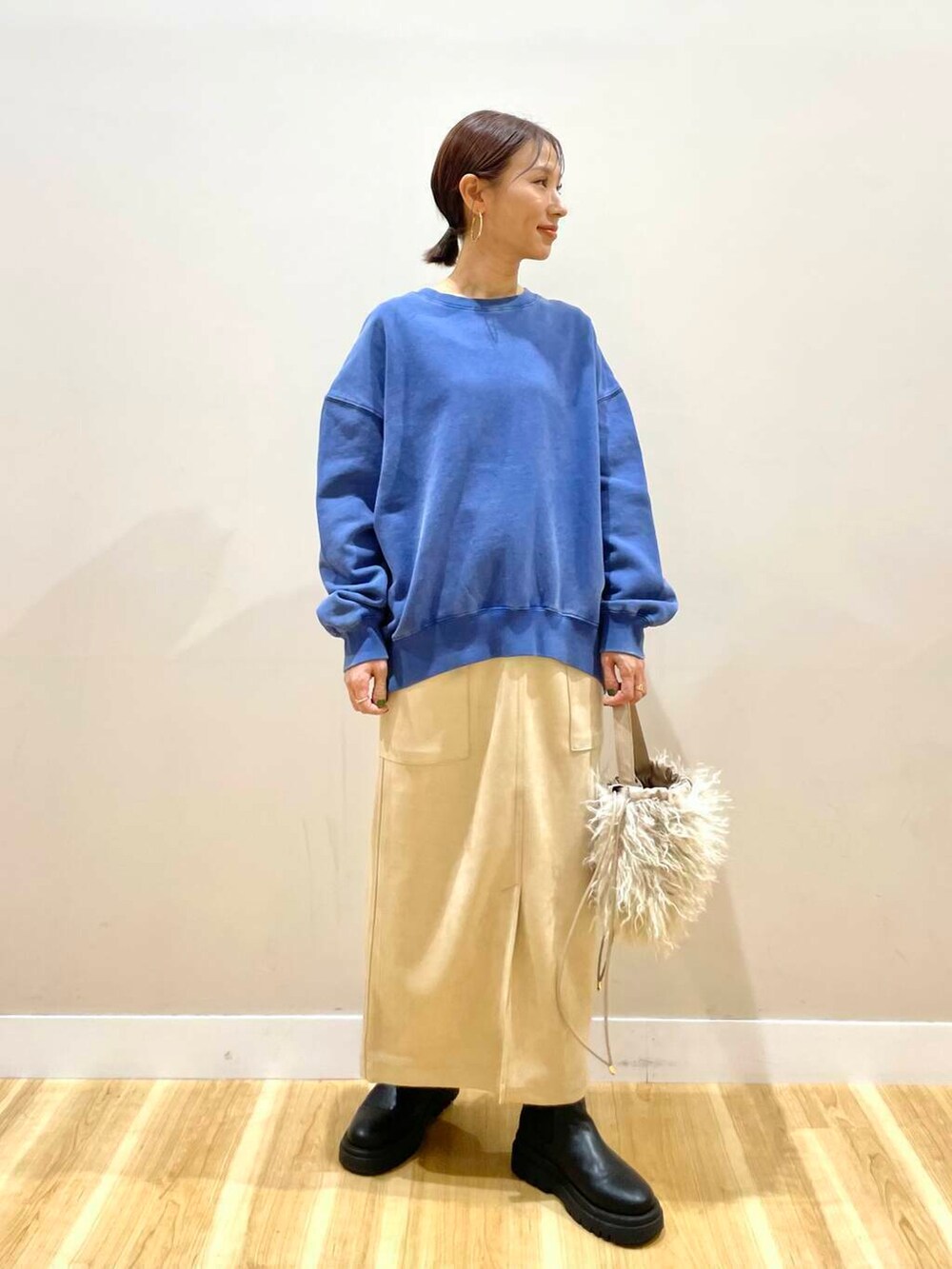 ベージュ系のショルダーバッグ、ホワイト系のスカート、グレー系のパーカーを着用したレディースの冬コーディネートの4枚目の写真