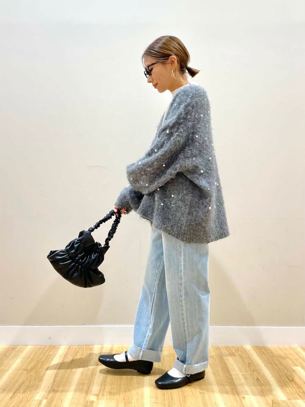 ブラック系のパンプス、ブラック系のハンドバッグ、ブルー系のデニムパンツを着用したレディースの秋コーディネートの7枚目の写真