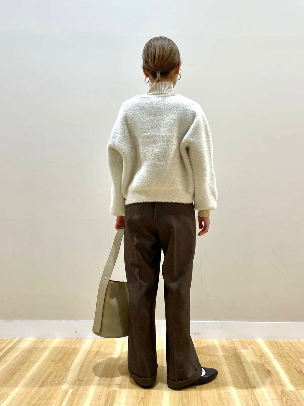 ブラック系のパンプス、ホワイト系のニット/セーター、ベージュ系のハンドバッグを着用したレディースの冬コーディネートの3枚目の写真