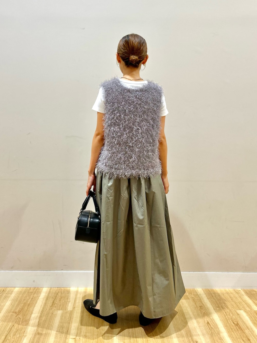 グレー系のベスト、ホワイト系のTシャツ/カットソー、グリーン系のスカートを着用したレディースの夏コーディネートの3枚目の写真