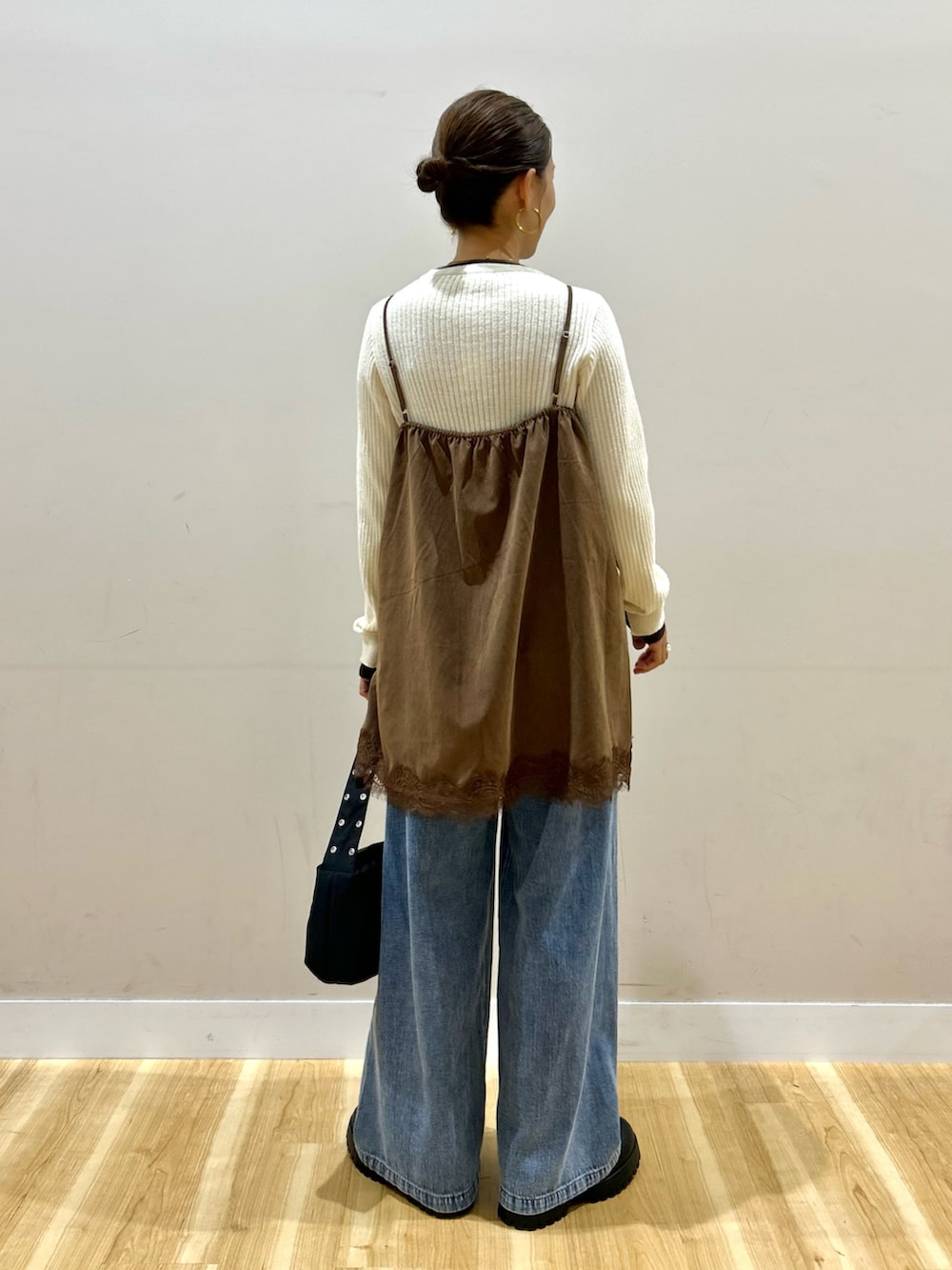 ブルー系のデニムパンツ、ブラック系のショルダーバッグ、ブラック系のブーツを着用したレディースの秋コーディネートの3枚目の写真