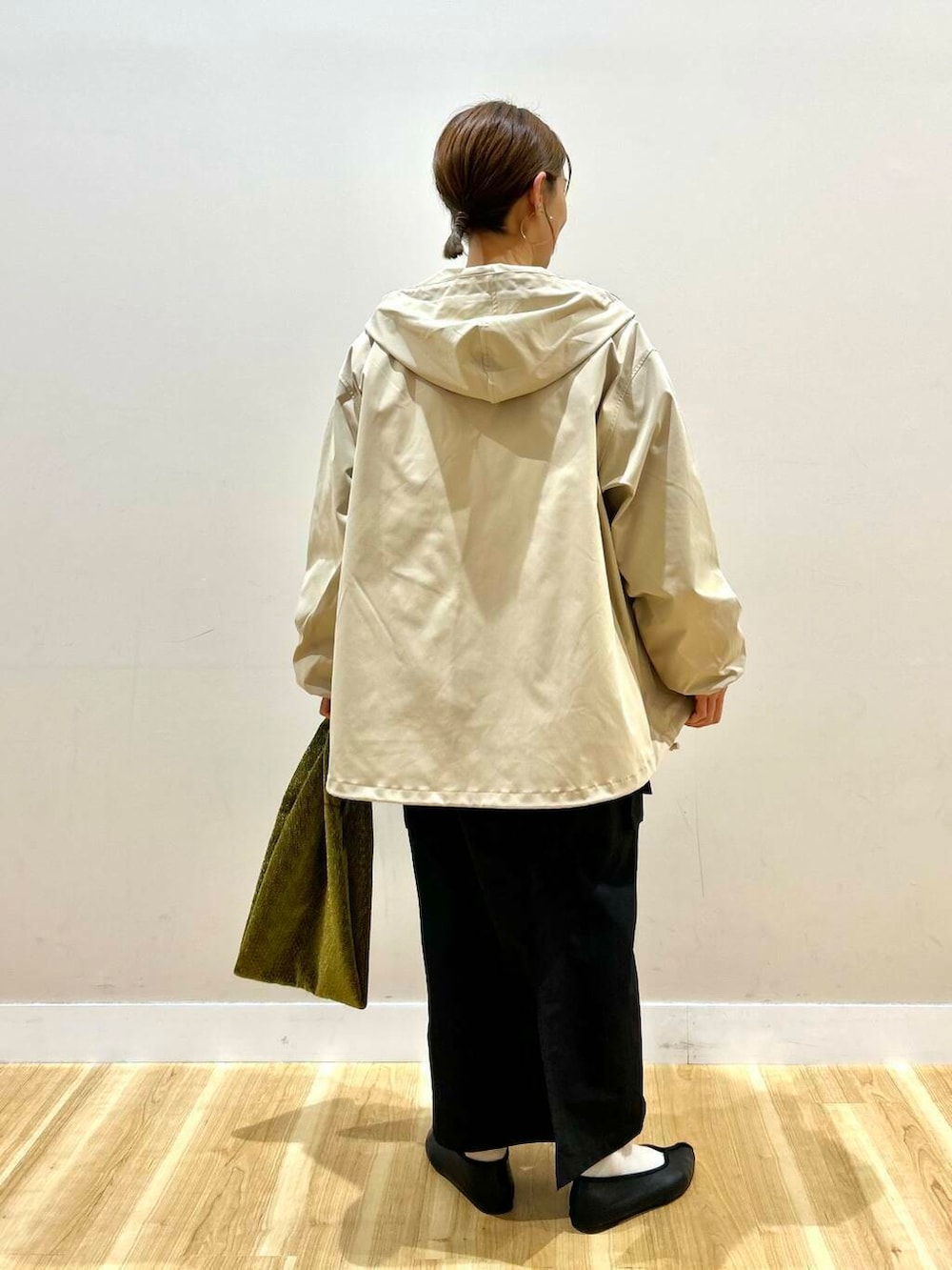 ゴールド系のトートバッグ、ベージュ系のマウンテンパーカー、ホワイト系のスウェットを着用したレディースの冬コーディネートの3枚目の写真