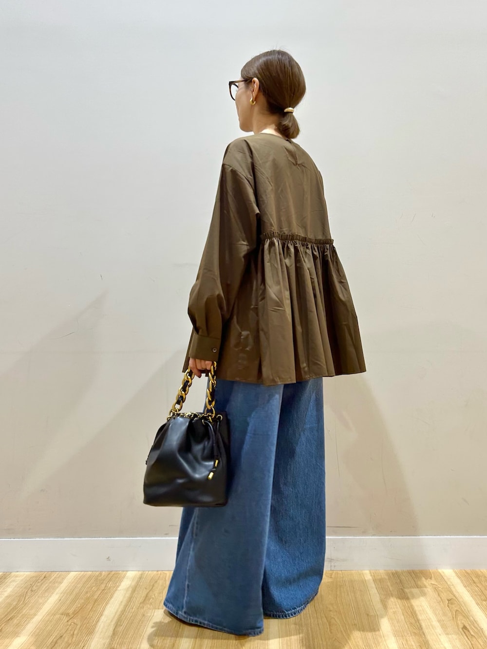 ブラウン系のシャツ/ブラウス、ブルー系のデニムパンツ、ブラック系のショルダーバッグを着用したレディースの秋コーディネートの4枚目の写真