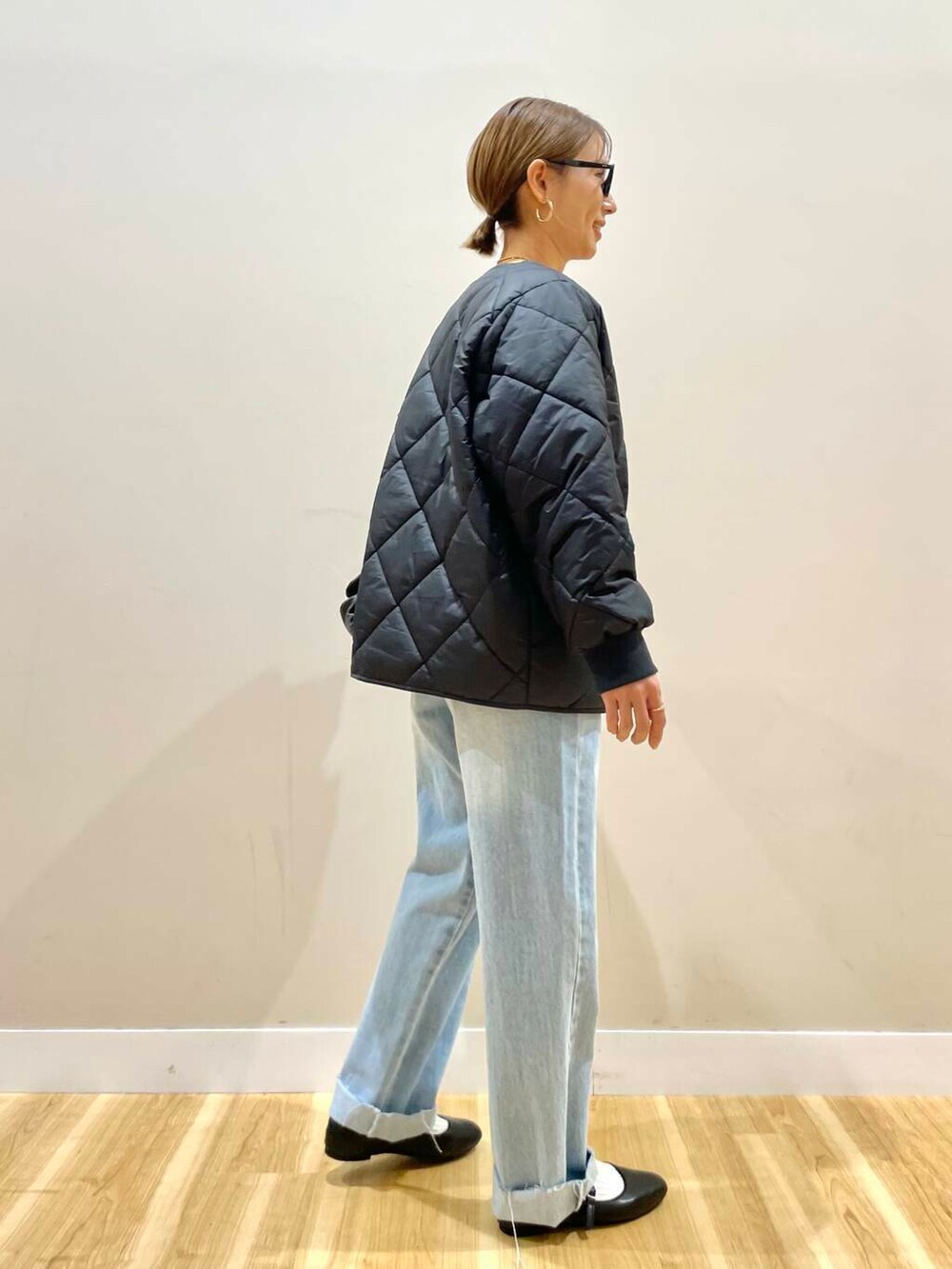 ブラック系のパンプス、ベージュ系のニット/セーター、ブルー系のデニムパンツを着用したレディースの冬コーディネートの4枚目の写真