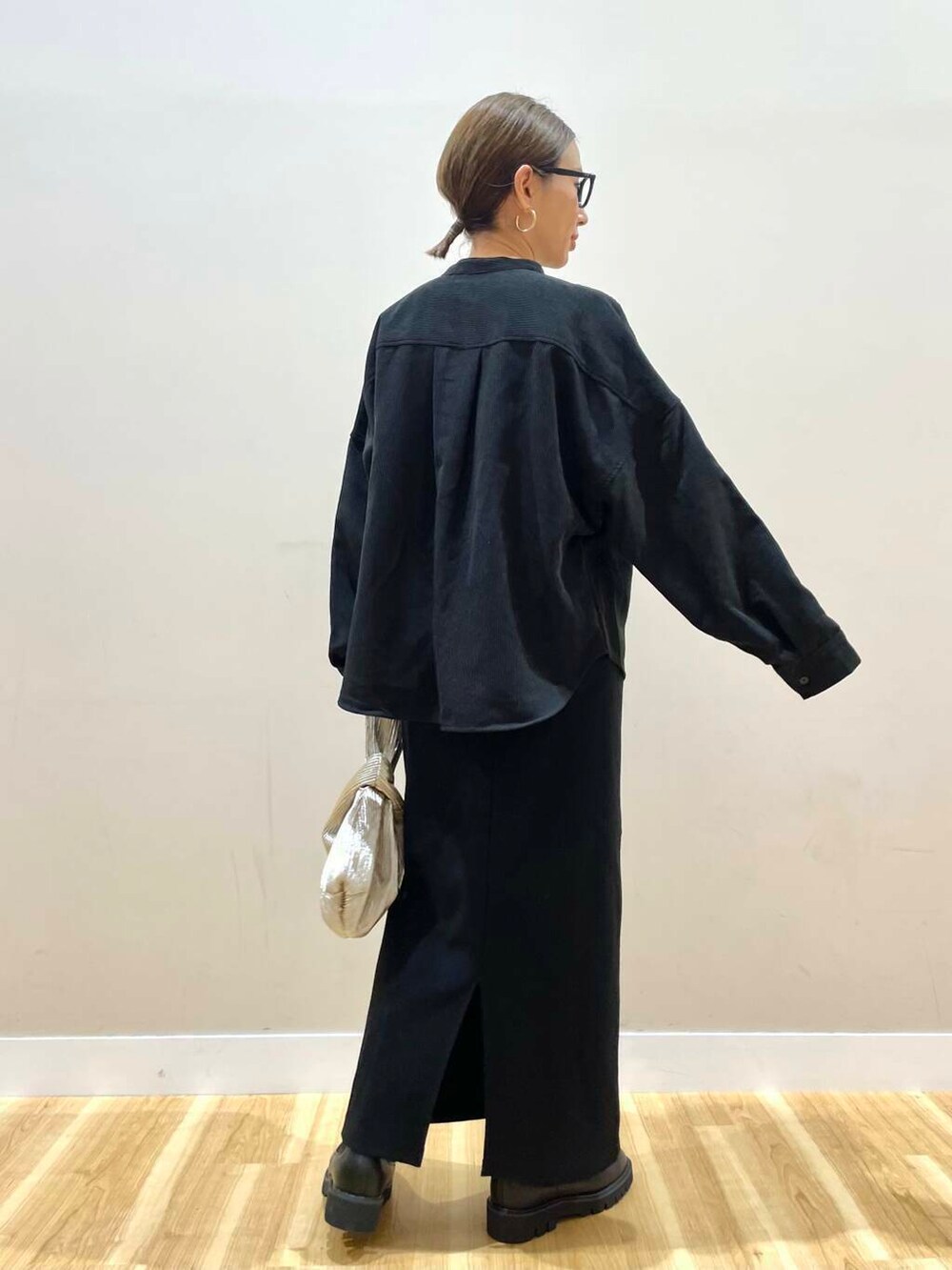 ブラック系のブーツ、グレー系のベスト、ゴールド系のハンドバッグを着用したレディースの秋コーディネートの9枚目の写真