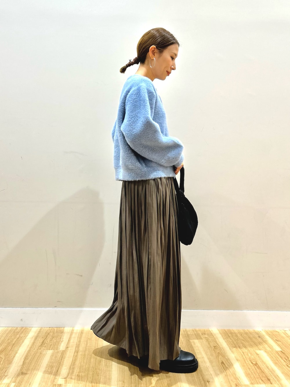 ブルー系のカーディガン/ボレロ、ベージュ系のスカート、ブラック系のハンドバッグを着用したレディースの秋コーディネートの2枚目の写真