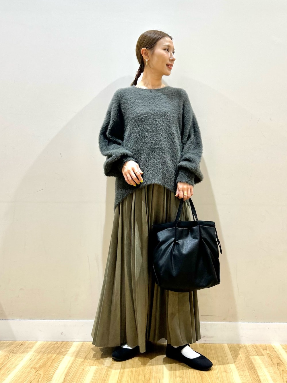 グレー系のニット/セーター、グリーン系のスカート、ブラック系のショルダーバッグを着用したレディースの秋コーディネートの7枚目の写真