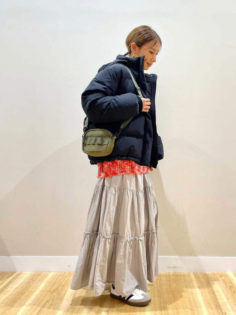 ブラック系のダウンジャケット/コート、グリーン系のショルダーバッグ、レッド系のニット/セーターを着用したレディースの冬コーディネートの2枚目の写真