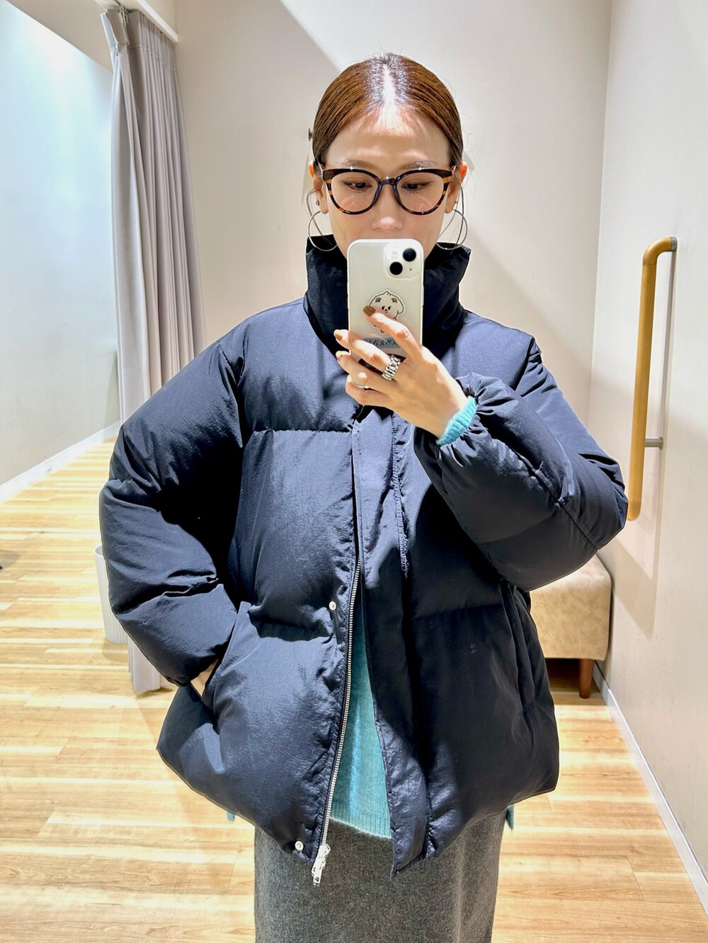 ブラック系のダウンジャケット/コート、ブルー系のニット/セーター、グレー系のスカートを着用したレディースの冬コーディネートの9枚目の写真