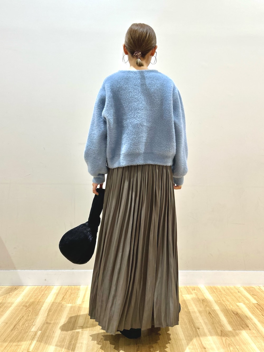 ブルー系のカーディガン/ボレロ、ベージュ系のスカート、ブラック系のハンドバッグを着用したレディースの秋コーディネートの3枚目の写真