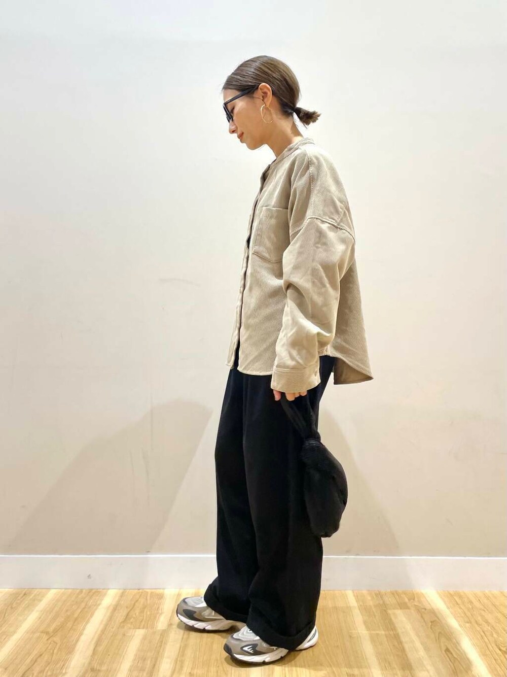 ブラック系のハンドバッグ、ベージュ系のTシャツ/カットソー、ブラック系のチノパンツを着用したレディースの秋コーディネートの4枚目の写真