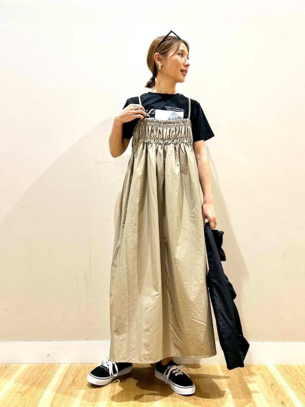 ブラック系のスニーカー、ブラック系のトートバッグ、ベージュ系のワンピースを着用したレディースの春コーディネートの2枚目の写真