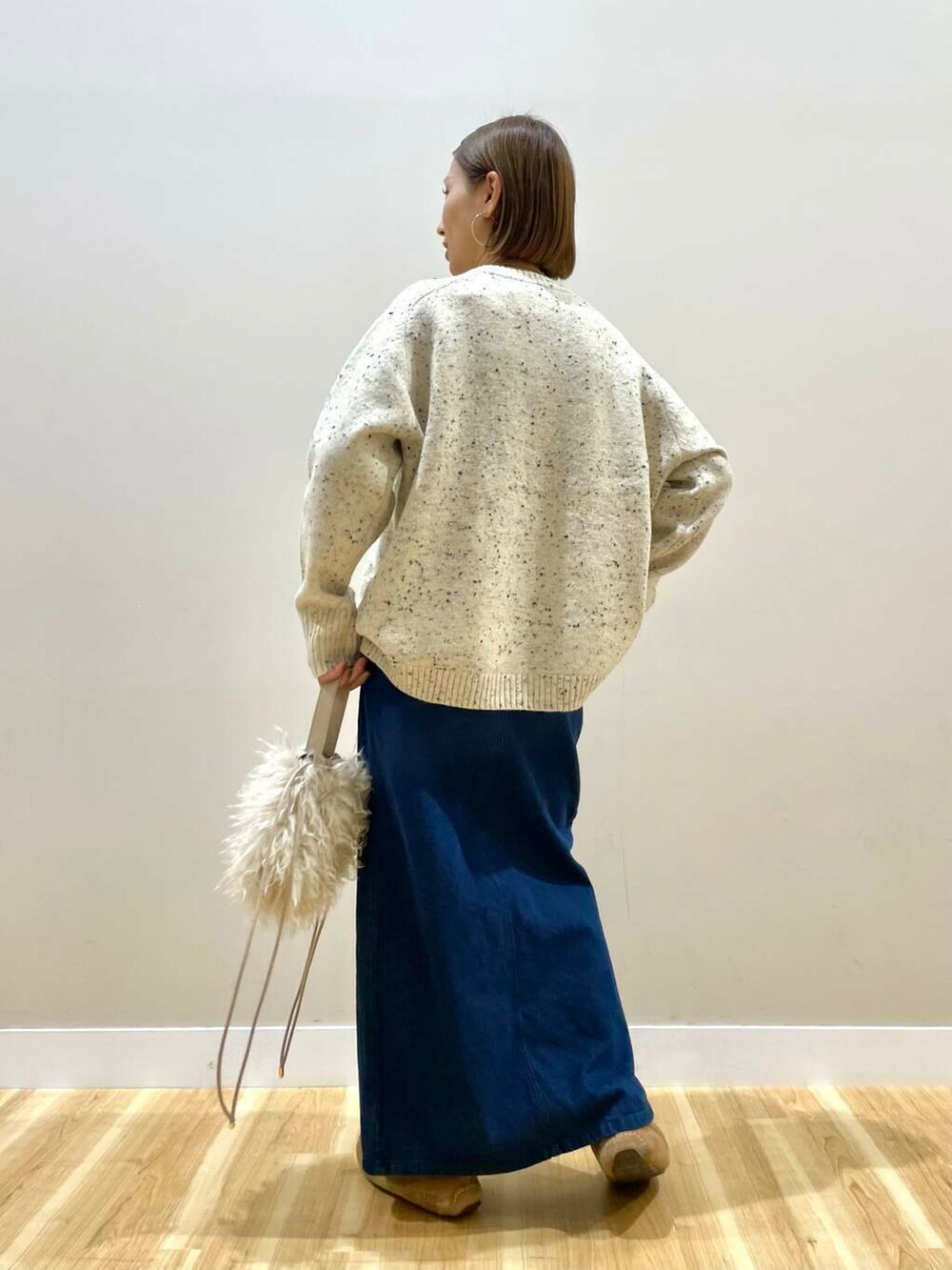 ベージュ系のショルダーバッグ、ブルー系のスカート、ベージュ系のダウンジャケット/コートを着用したレディースの秋コーディネートの8枚目の写真