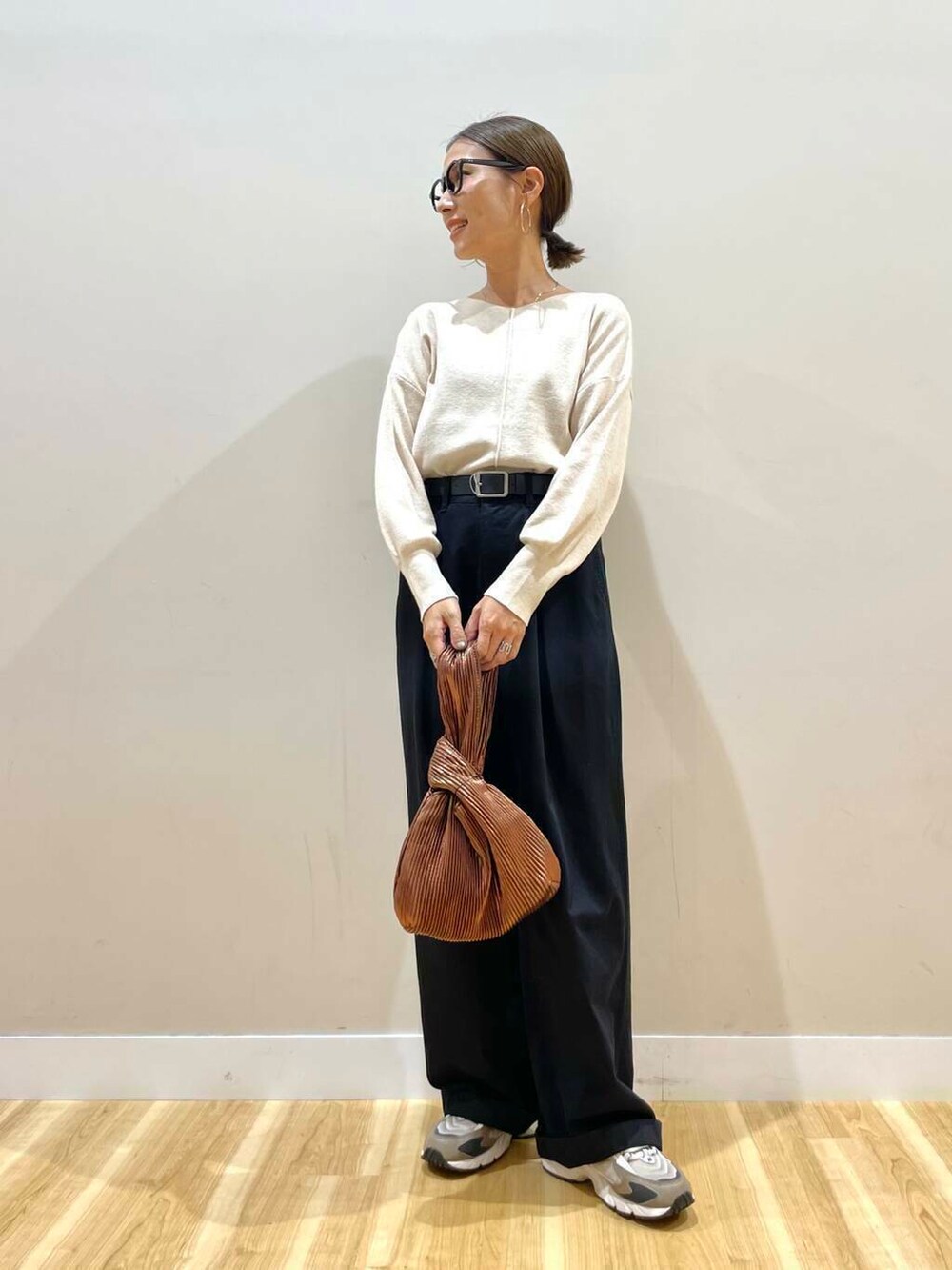 ホワイト系のニット/セーター、ブラウン系のハンドバッグ、ブラック系のその他アウターを着用したレディースの秋コーディネートの2枚目の写真