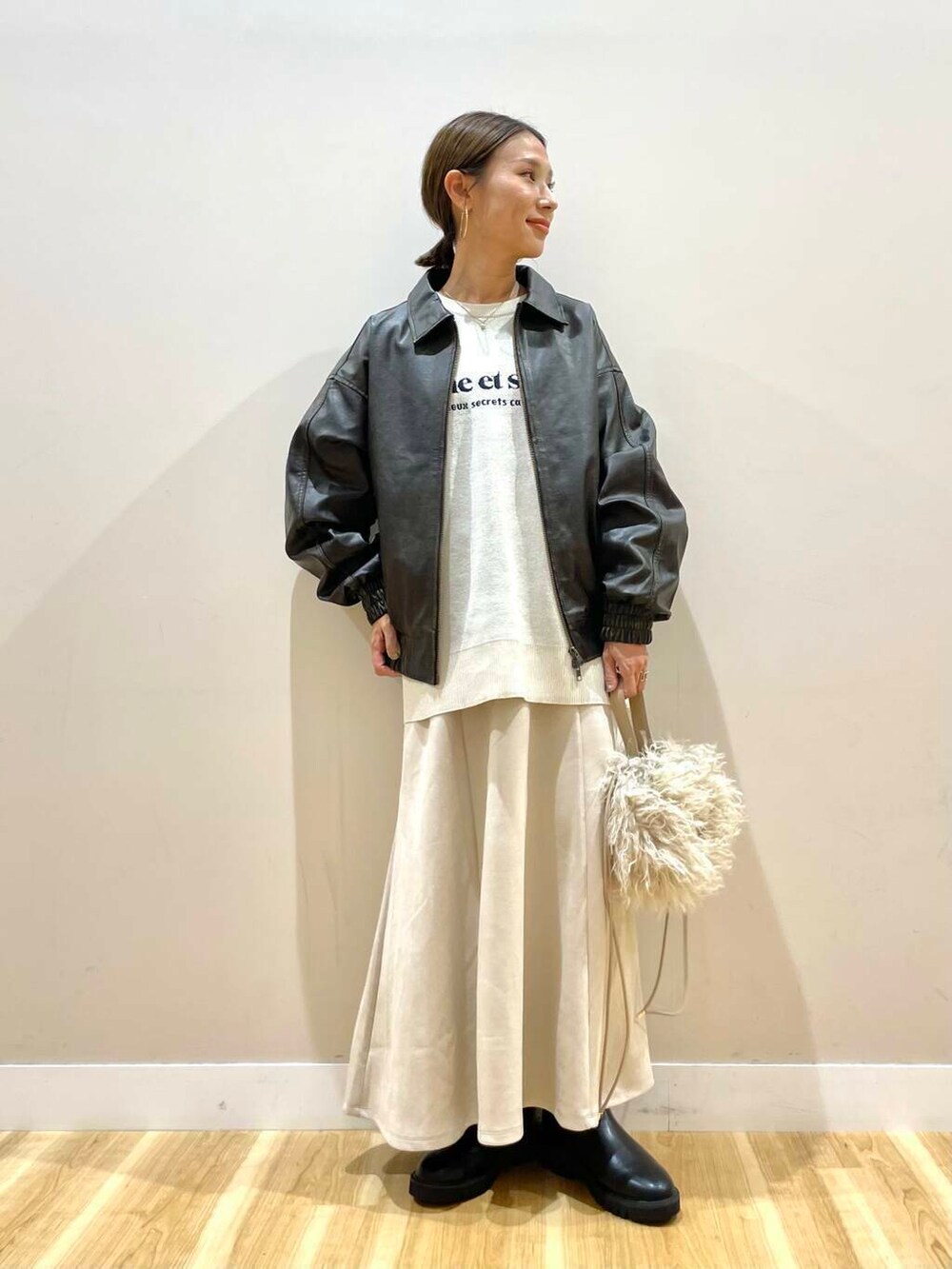 ブラック系のブーツ、ベージュ系のショルダーバッグ、ベージュ系のスカートを着用したレディースの秋コーディネートの6枚目の写真