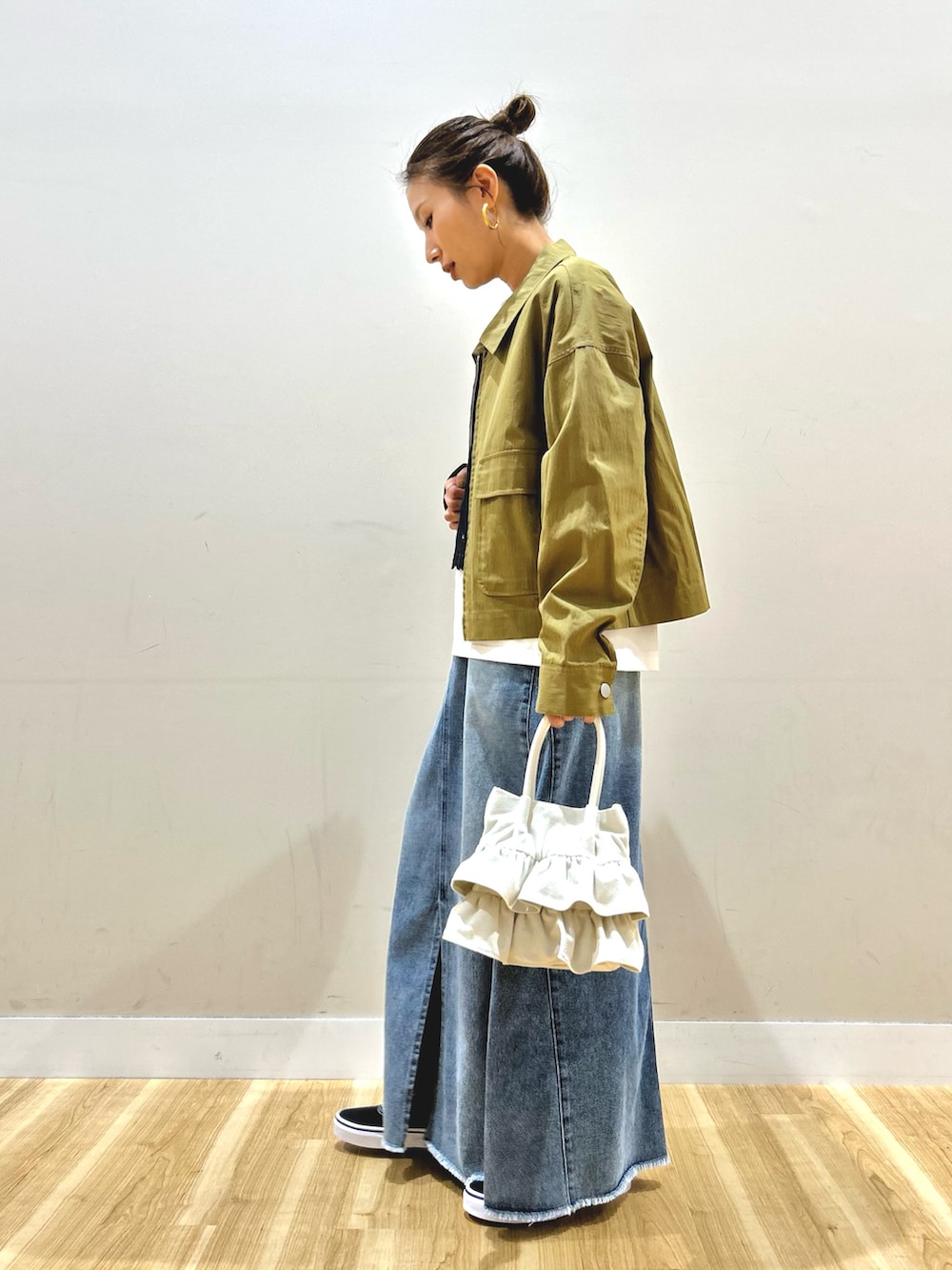 グリーン系のブルゾン、ブラック系のTシャツ/カットソー、ブルー系のスカートを着用したレディースの春コーディネートの3枚目の写真