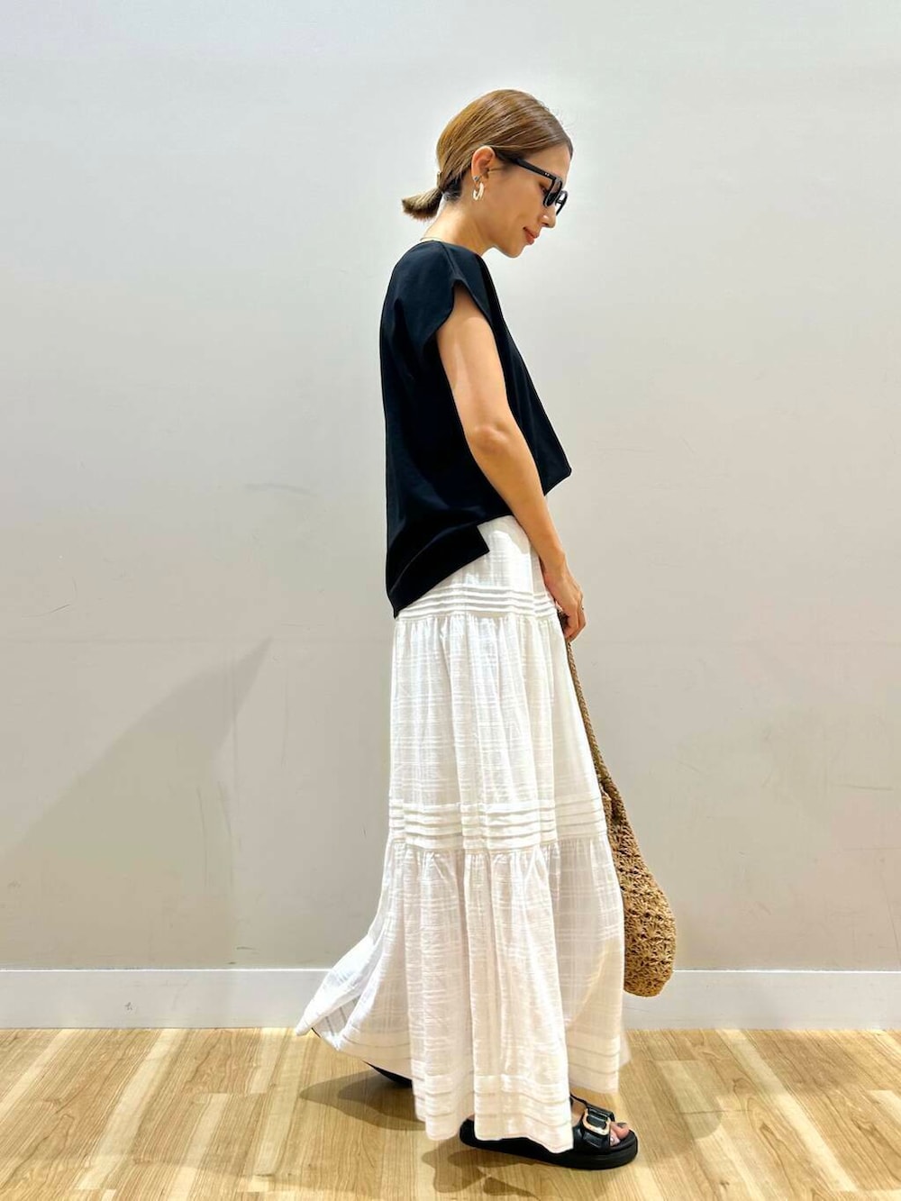 ブラック系のサンダル、ベージュ系のトートバッグ、ホワイト系のスカートを着用したレディースの夏コーディネートの3枚目の写真