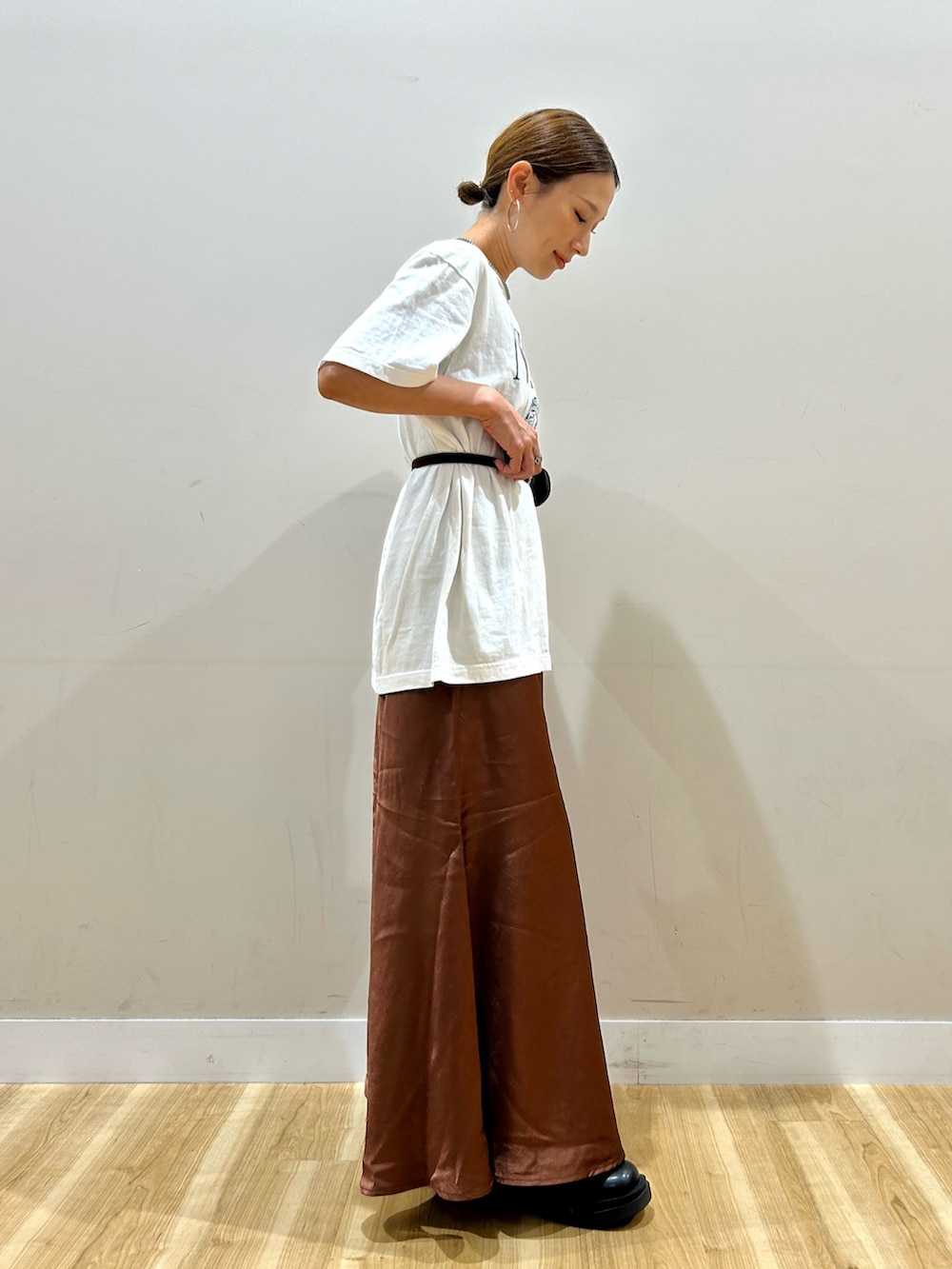ホワイト系のTシャツ/カットソー、ブラウン系のスカート、ブラック系のブーツを着用したレディースの夏コーディネートの2枚目の写真