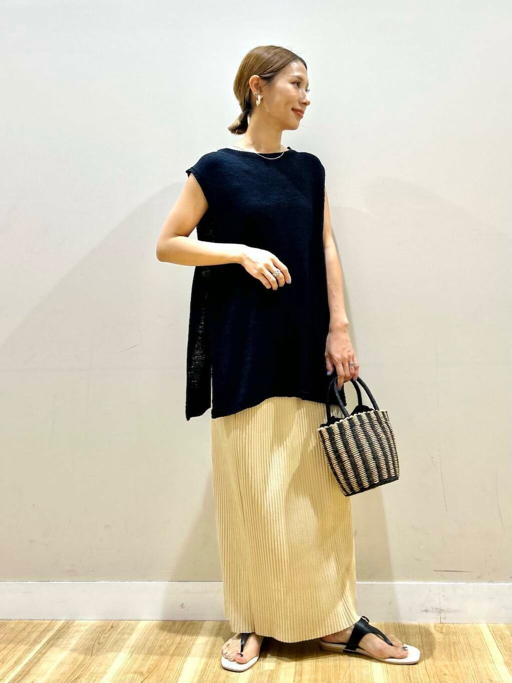 ベージュ系のタンクトップ、ブラック系のハンドバッグ、ブラック系のサンダルを着用したレディースの夏コーディネートの2枚目の写真