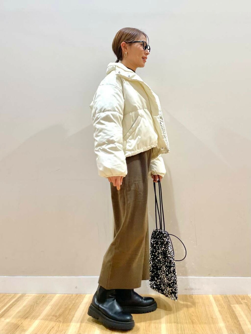 ブラウン系のワンピース、シルバー系のトートバッグ、ホワイト系のダウンジャケット/コートを着用したレディースの冬コーディネートの2枚目の写真