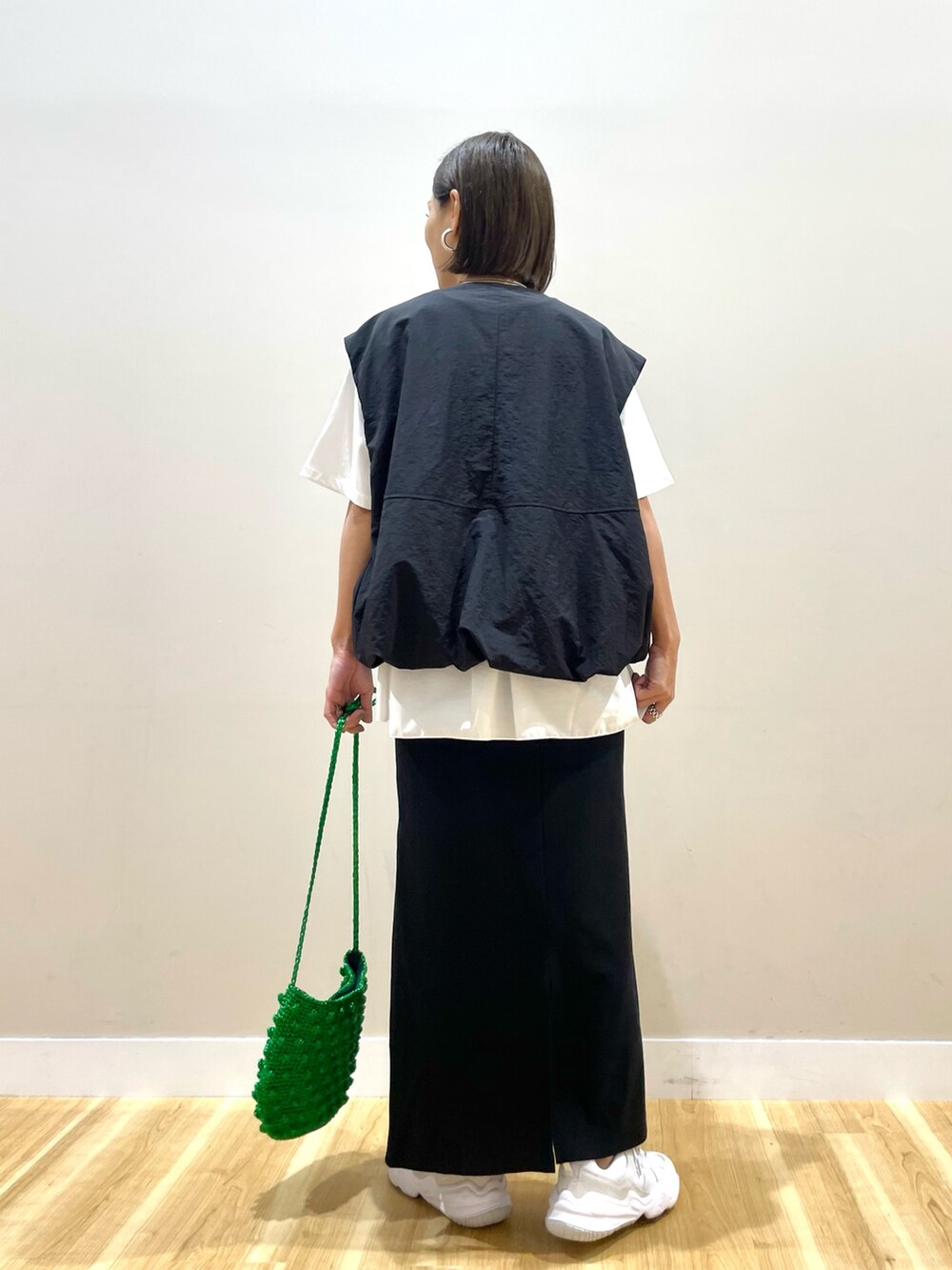 ブラック系のベスト、ホワイト系のTシャツ/カットソー、ブラック系のスカートを着用したレディースの秋コーディネートの3枚目の写真