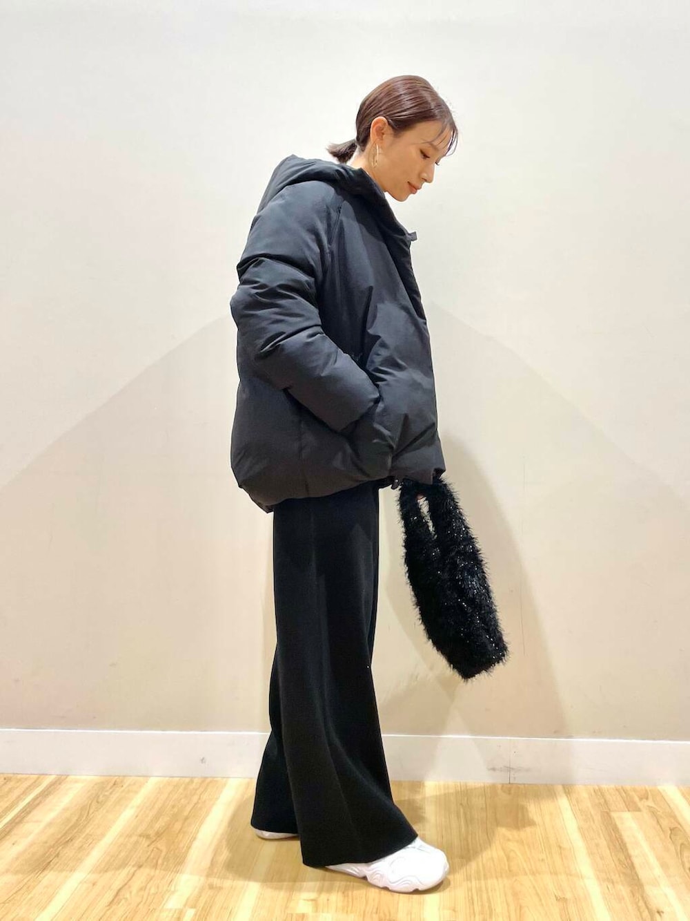 ホワイト系のスニーカー、ベージュ系のTシャツ/カットソー、ブラック系のダウンジャケット/コートを着用したレディースの冬コーディネートの5枚目の写真