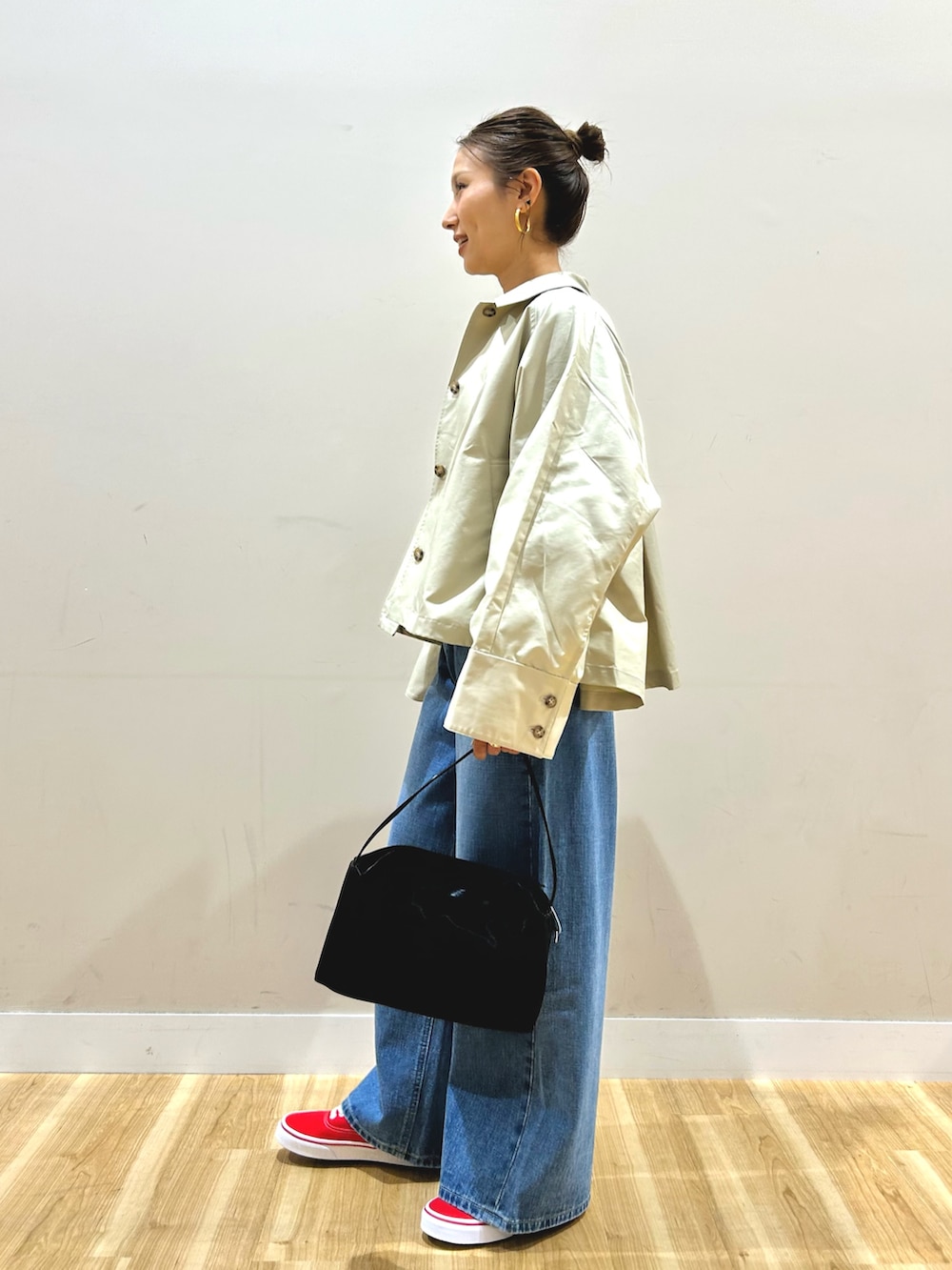 グレー系のステンカラーコート、グレー系のTシャツ/カットソー、ブルー系のデニムパンツを着用したレディースの春コーディネートの2枚目の写真